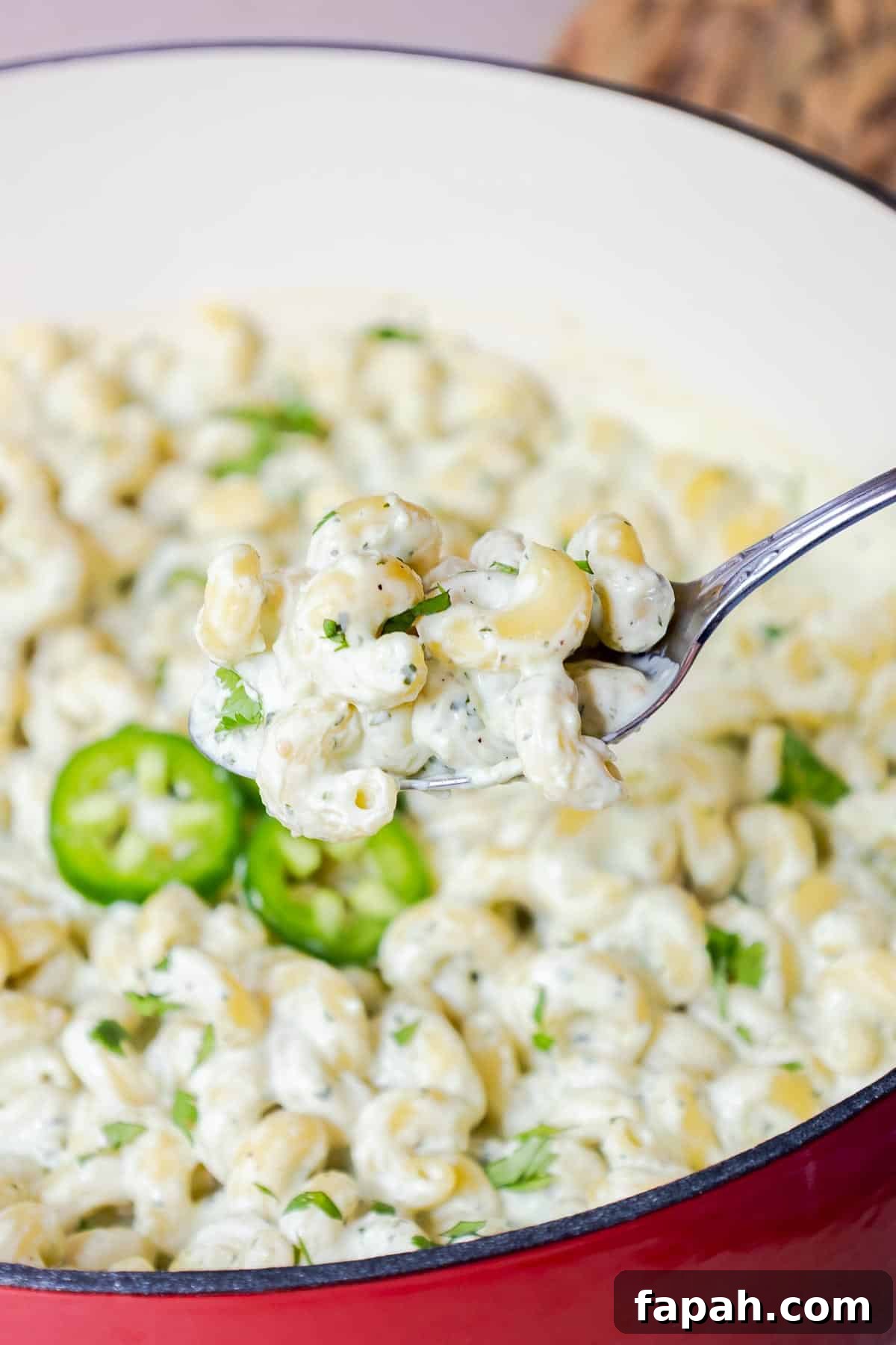 Creamy Jalapeño Ranch Pasta Recipe for a Flavorful Weeknight Meal 11 A spoon lifting creamy pasta from a pot with jalapeños and cilantro.