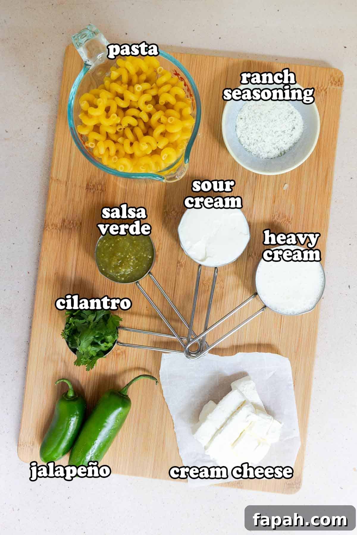 Creamy Jalapeño Ranch Pasta Recipe for a Flavorful Weeknight Meal 3 Ingredients on a board: dry pasta, ranch seasoning, sour cream, heavy cream, salsa verde, cilantro, jalapeños, and cream cheese.