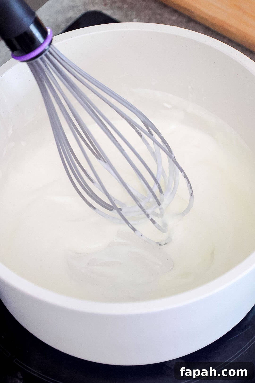 Creamy Jalapeño Ranch Pasta Recipe for a Flavorful Weeknight Meal 6 A whisk in a saucepan of white cream mixture.