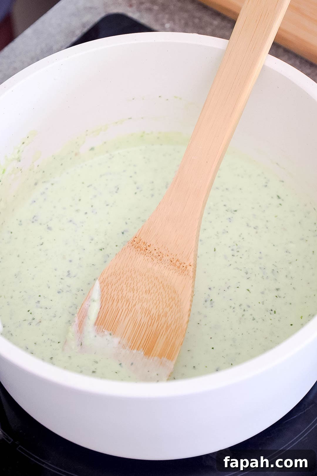 Creamy Jalapeño Ranch Pasta Recipe for a Flavorful Weeknight Meal 7 A saucepan with creamy jalapeño sauce and a wooden spoon.