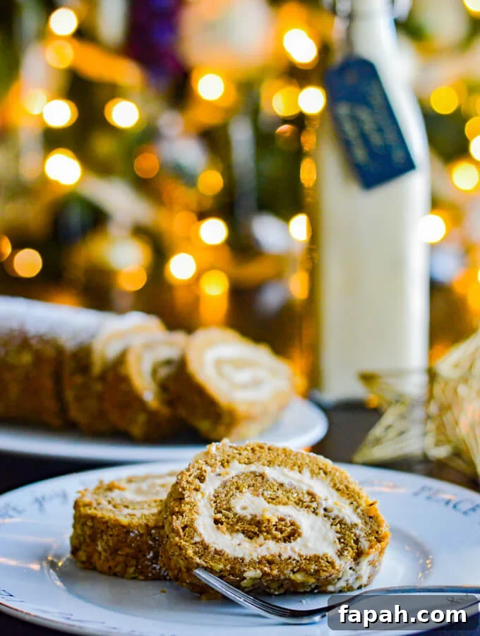 Salted Caramel Pumpkin Cake Roll Recipe for Fall Desserts 2 Two slices of pumpkin cake roll sit on a white plate with a fork. A plate of several slices and a jar of eggnog sits in the background. A Christmas tree with lights are blurred in the background.