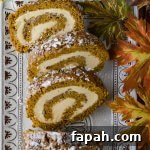 A pumpkin cake roll with three slices cut on a serving tray with fall leaves next to it.