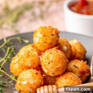 A pile of fried goat cheese balls on a plate with honey on top.