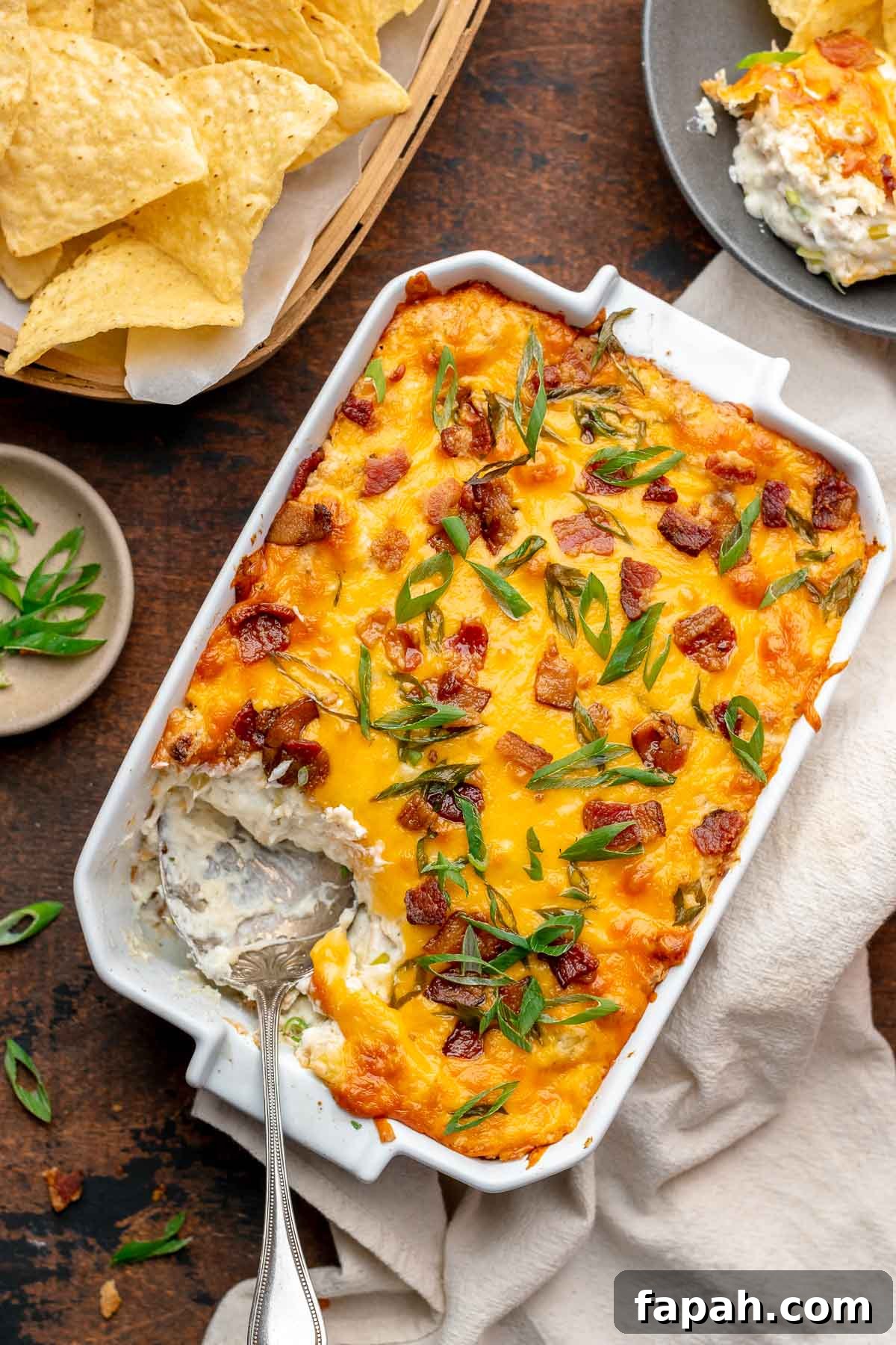 Cheesy Chicken Bacon Ranch Dip — Oven or Crockpot Recipe 8 A spoon scoops out a spoonful of chicken bacon ranch dip from the corner of a casserole dish.