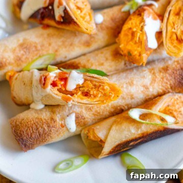 Buffalo chicken taquitos on a platter drizzled with ranch.