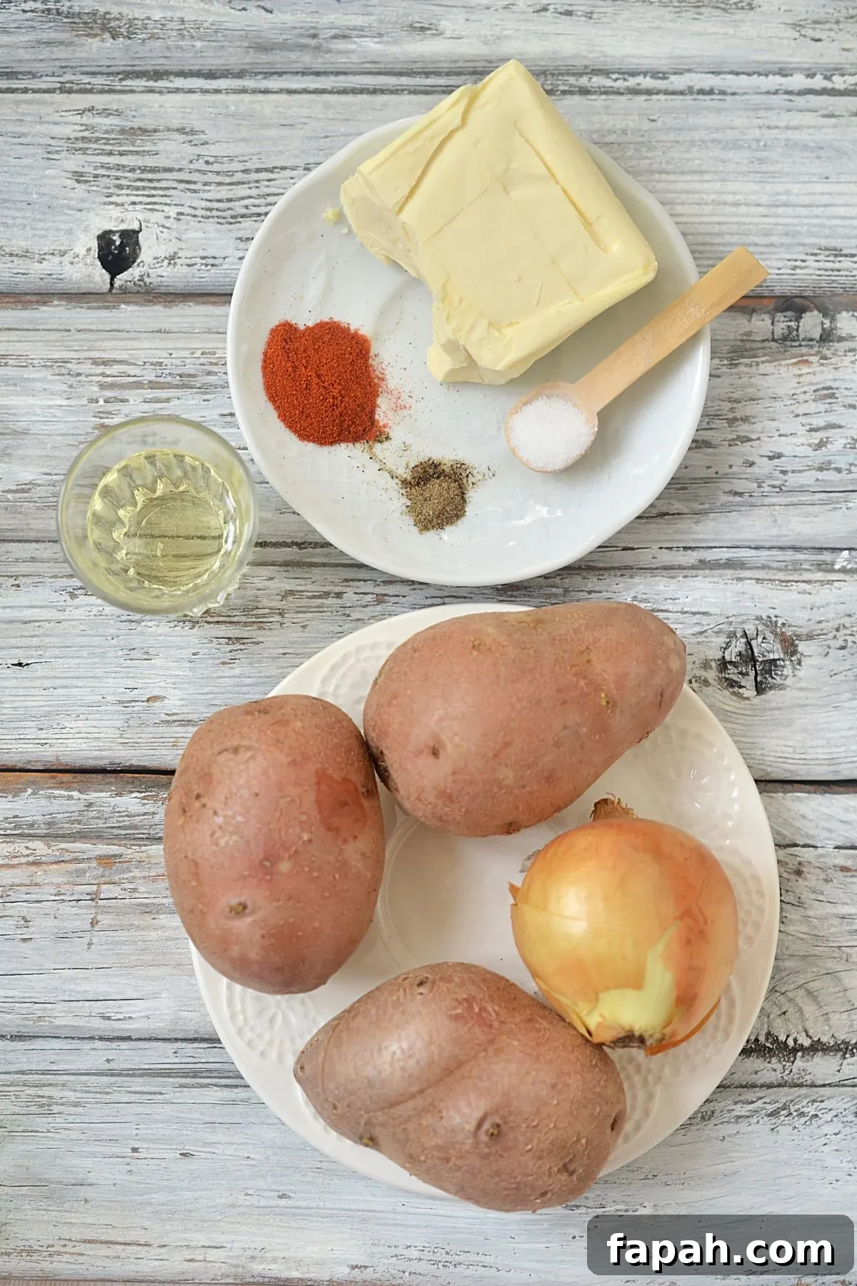 The ingredients needed to make fried potatoes and onions – potatoes onions oil and spices with butter.