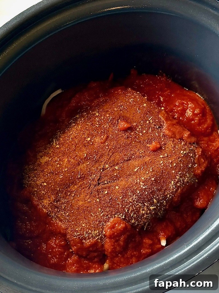 Seasoned pork roast on top of the veggies with fire roasted tomatoes around the pork
