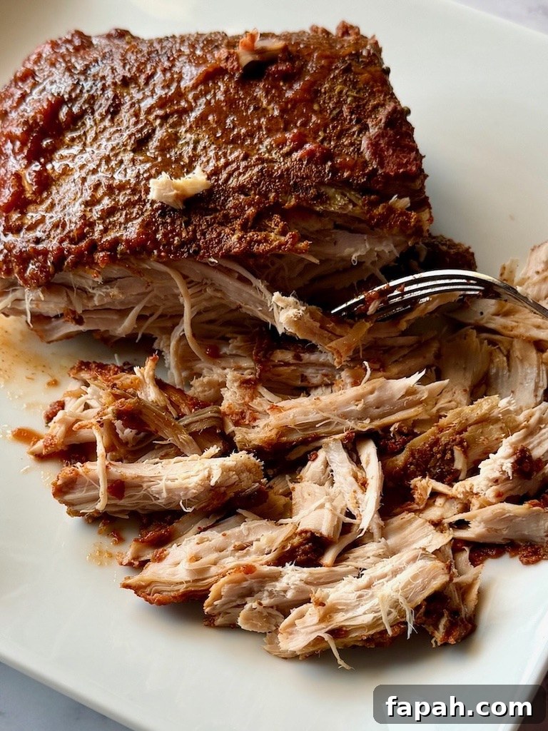 Pork roast on a plate shredded with a fork.
