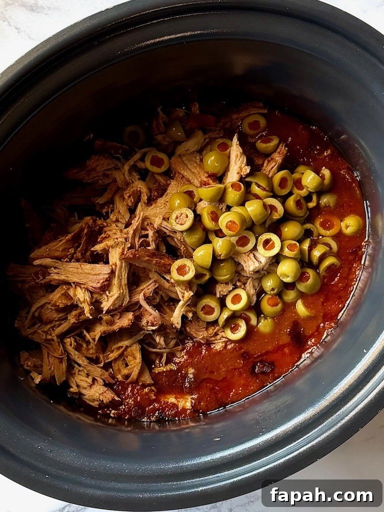 Green olives, pork, and red wine vinegar back in the slow cooker.