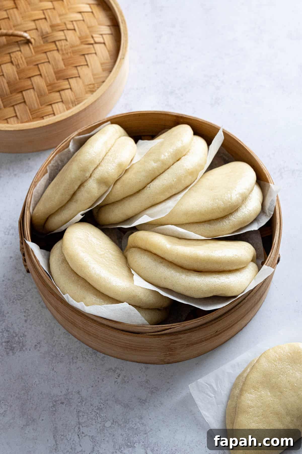 A pile of bao buns in a bamboo steamer.