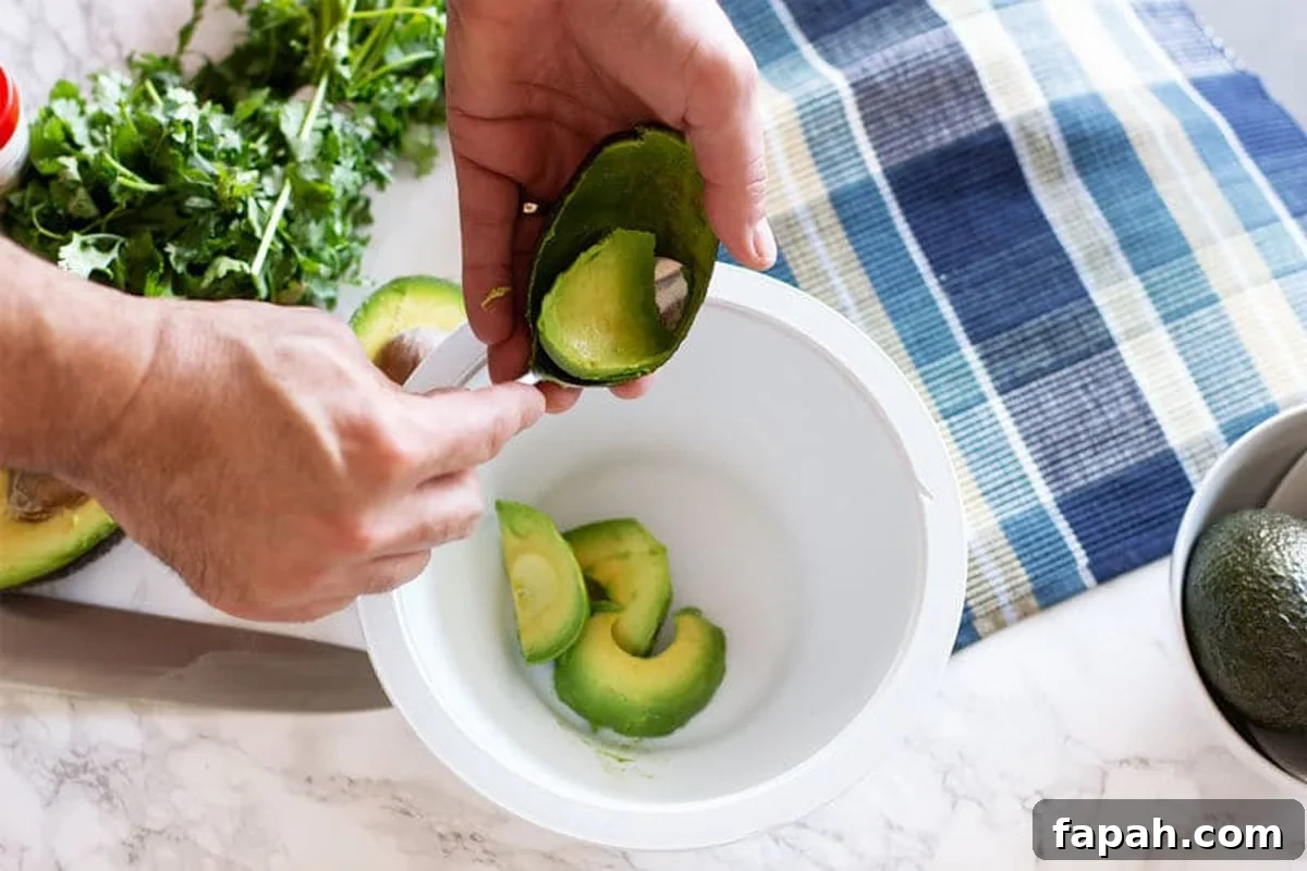 Creamy Homemade Guacamole Recipe for Parties and Everyday Meals 5 scooping the avocado into a bowl.