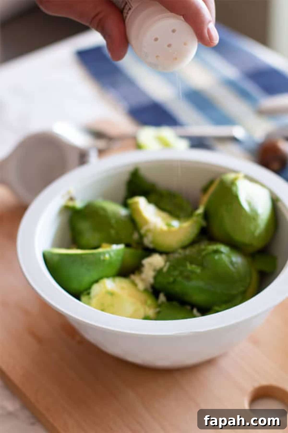 Creamy Homemade Guacamole Recipe for Parties and Everyday Meals 7 Adding garlic salt to the bowl of guacamole.