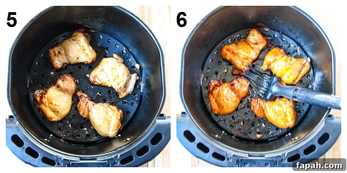 The chicken in the air fryer basket being brushed with teriyaki sauce in the final minutes of cooking.