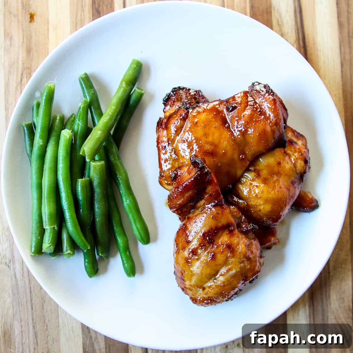 Three pieces of glazed chicken on a white plate.