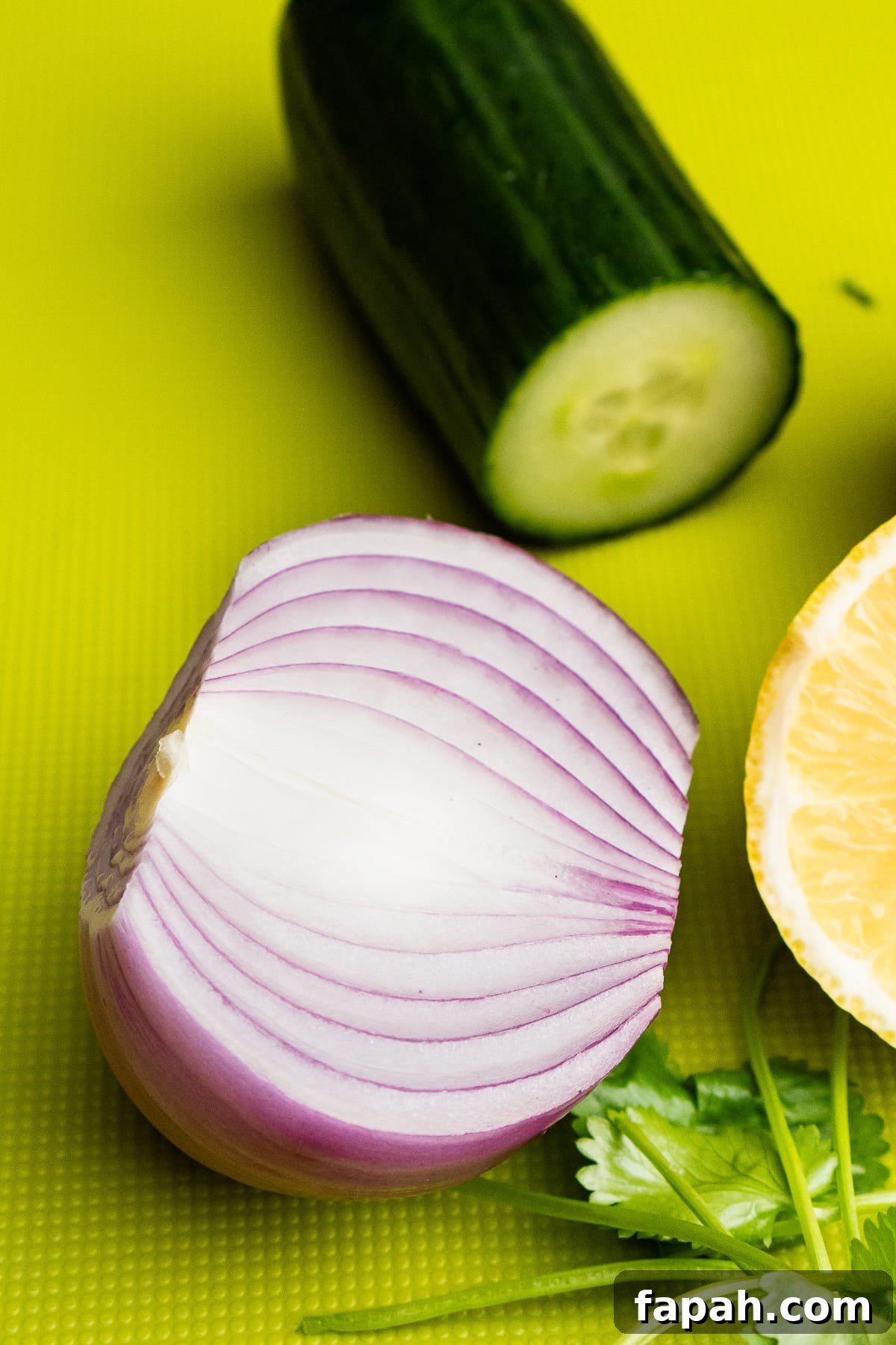 Half a red onion and a quarter of cucumber in the background