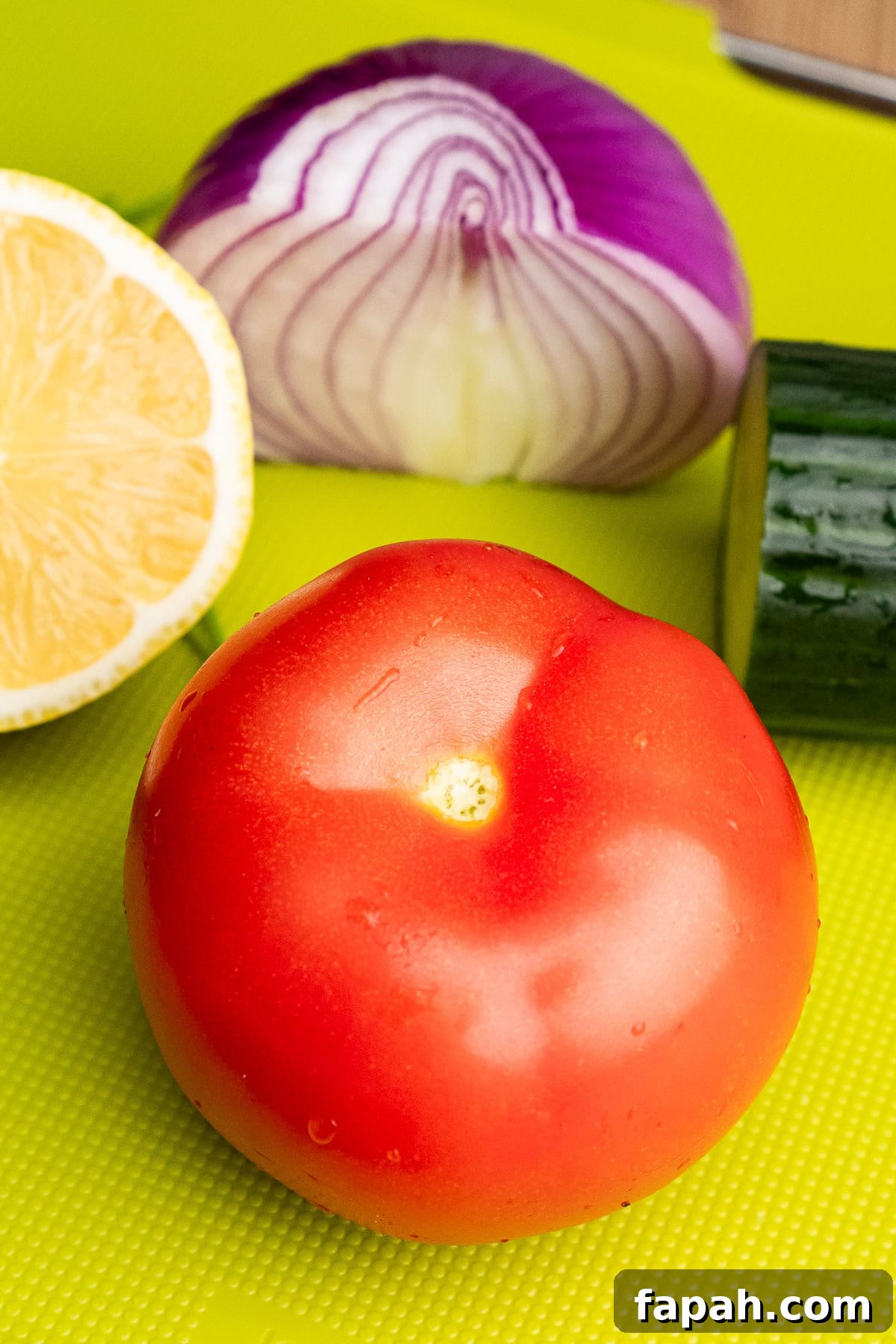 A tomato on a green chopping board