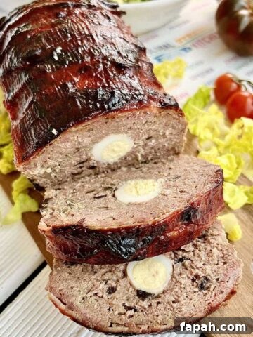 Smoked meatloaf on a wooden chopping board with salad and tomatoes around it.