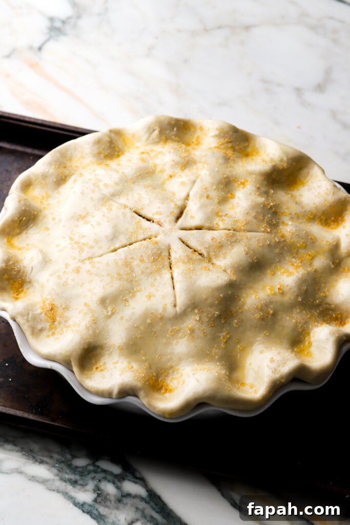 pie crust on top of the pie with slits in it and egg wash and sugar