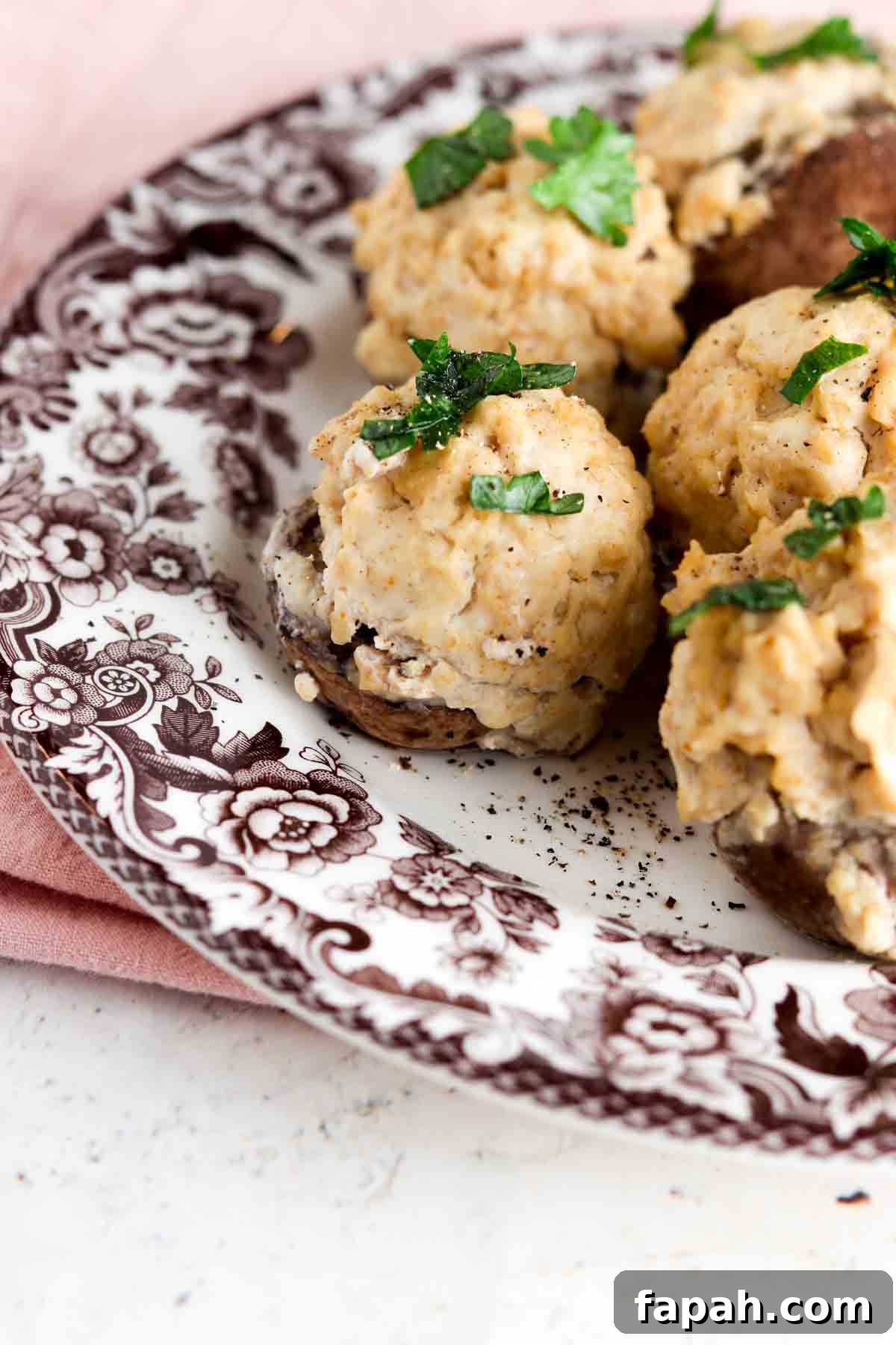 Stuffed mushrooms on a brown and white plate with fresh parsley on top.