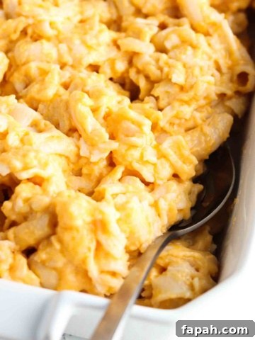 Gluten free mac and cheese in a white casserole dish with a metal serving spoon.