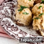 Stuffed mushrooms on a brown and white plate with fresh parsley on top.