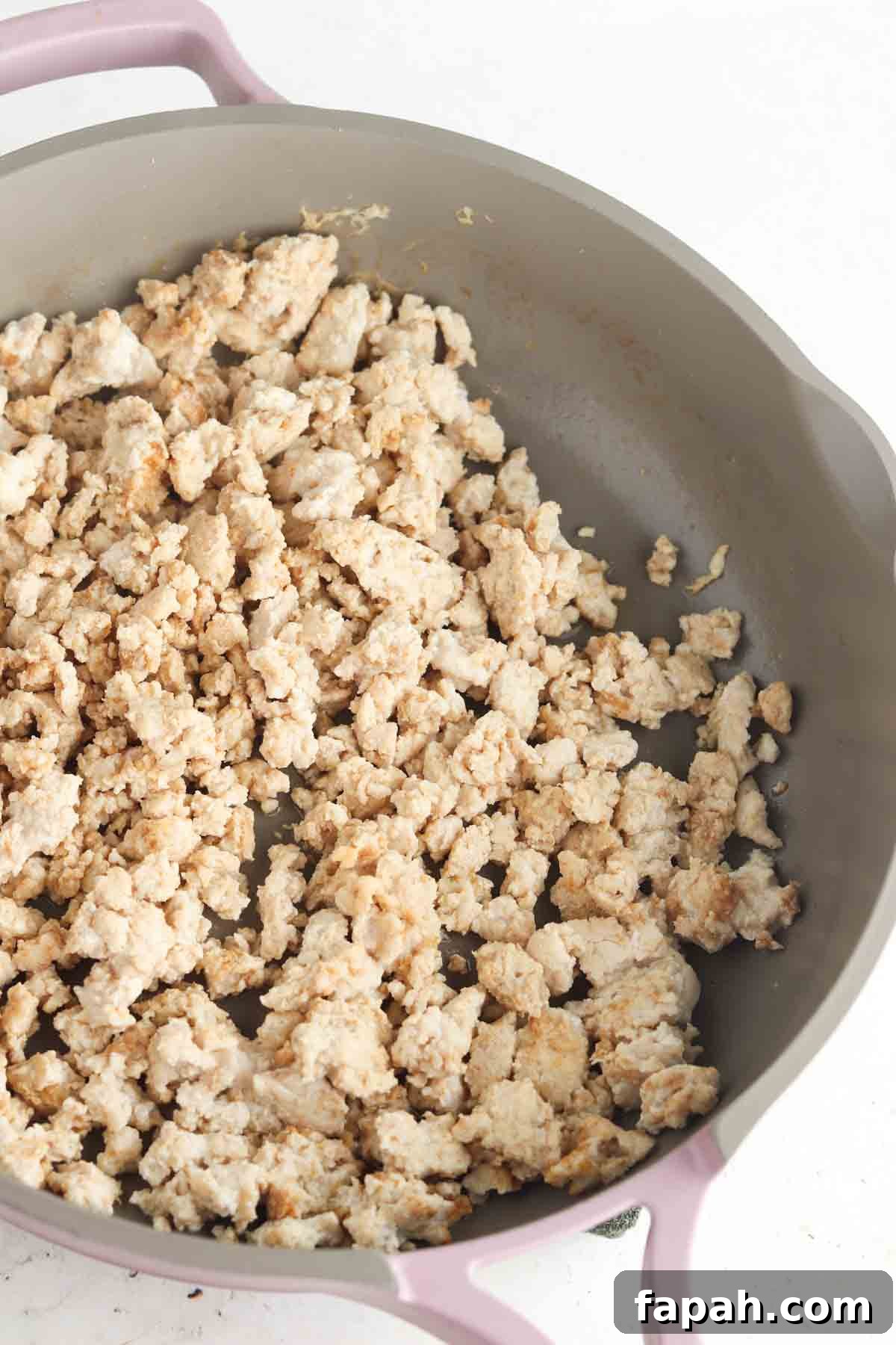 Ground chicken and spices in a frying pan.