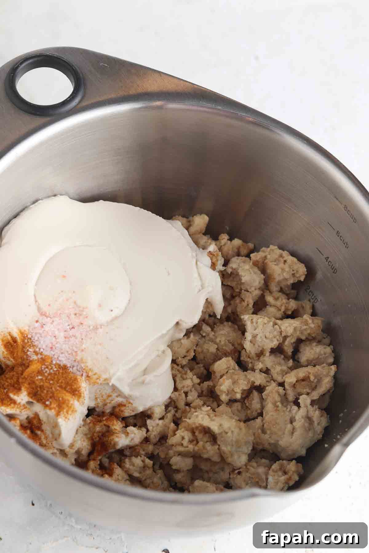 Cream cheese and spiced ground chicken in a large bowl.