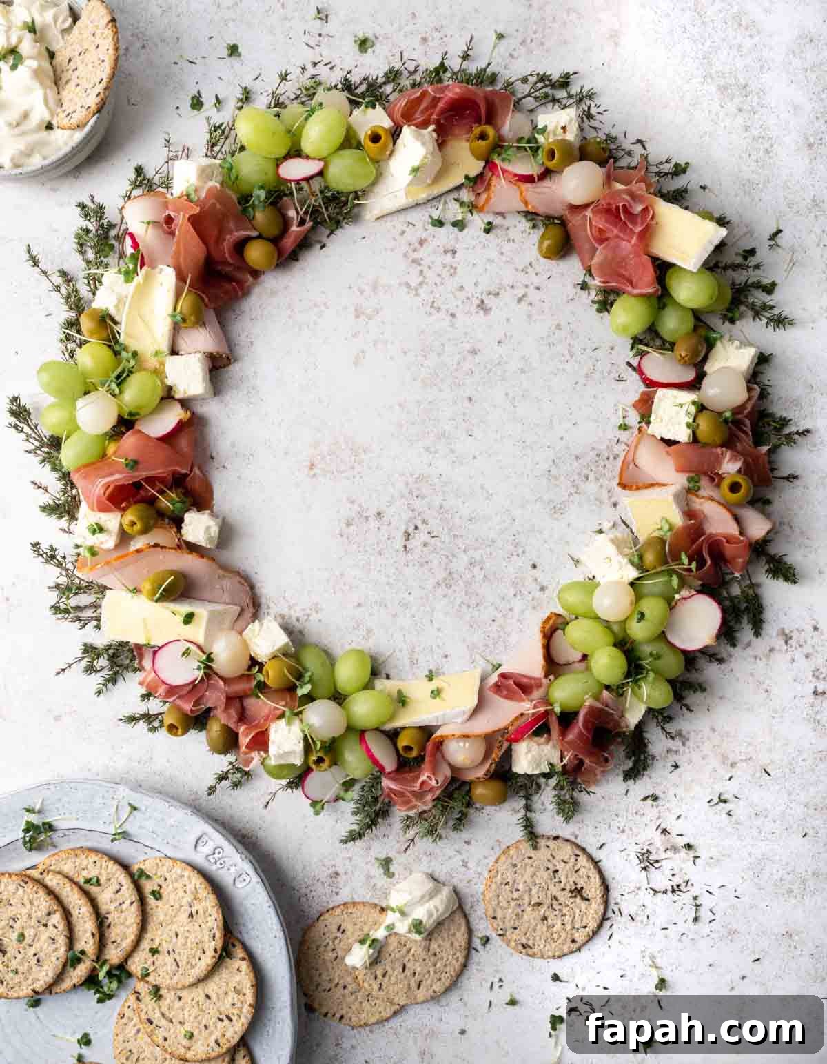 Christmas charcuterie board in a wreath shape with various meats, cheese and fruit.