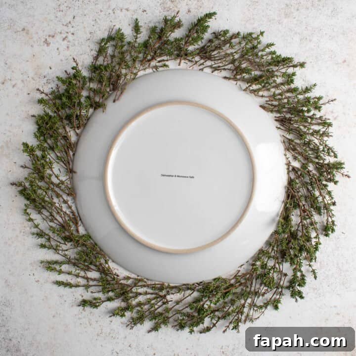 Christmas charcuterie board demonstration of how to build the perfect circle with herbs using a plate in the middle.