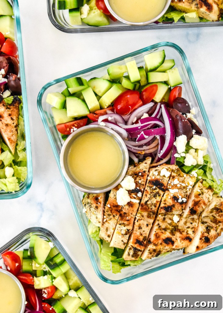 Greek chicken salad meal prep with dressing in a glass meal prep container.