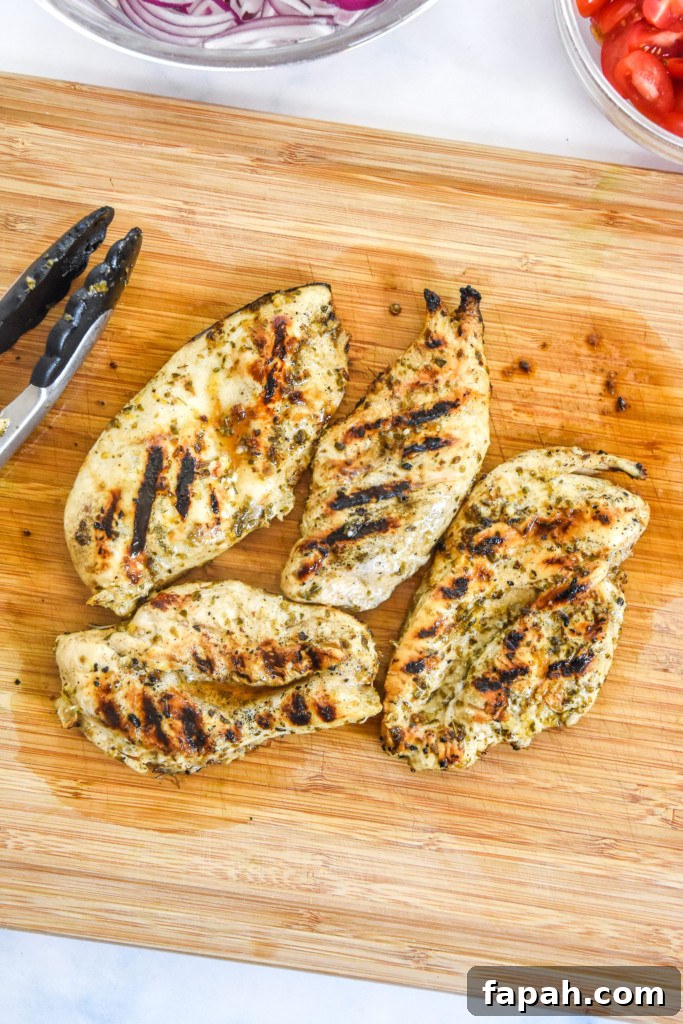 cooked charred greek chicken resting on a cutting board.