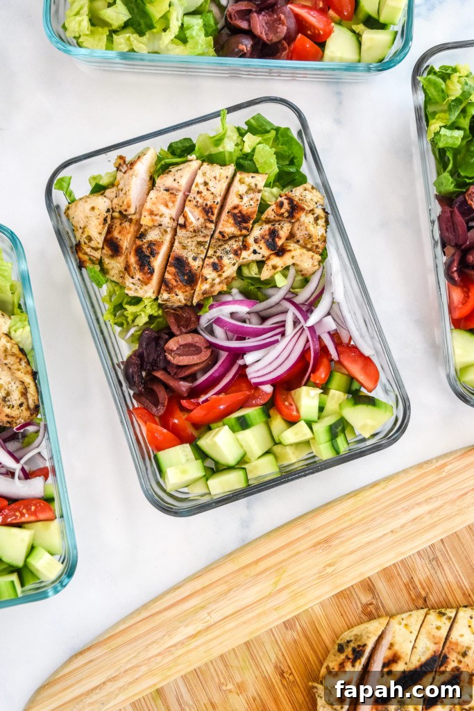 adding sliced chicken to the greek chicken salad meal prep bowls.