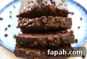 Banana chocolate bread sliced and sitting on a plate with chocolate chips scattered around the bread.