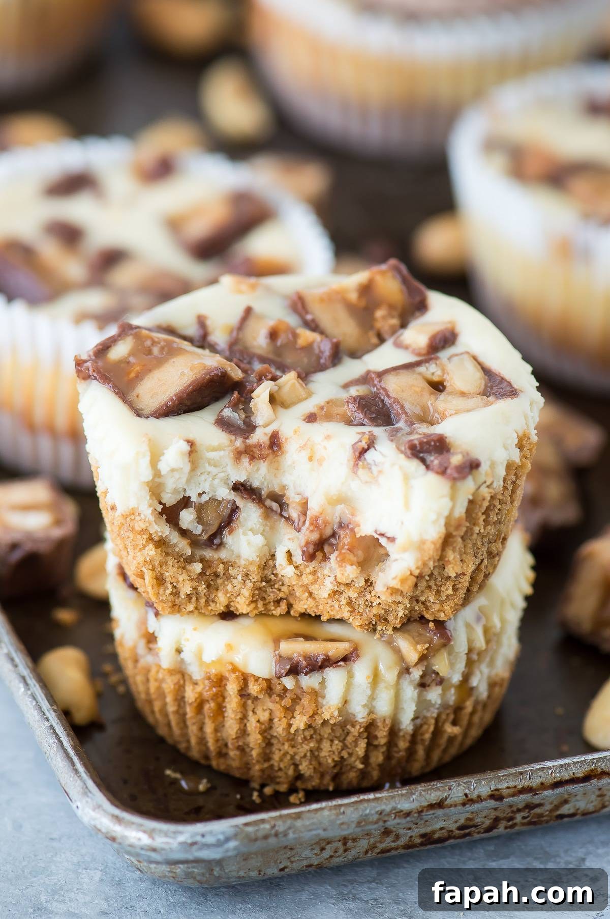 Mini Snickers Cheesecakes: Bite-Sized Candy Bar Desserts 4 mini snicker’s cheesecakes stacked 2 high with bite taken out of top cheesecake