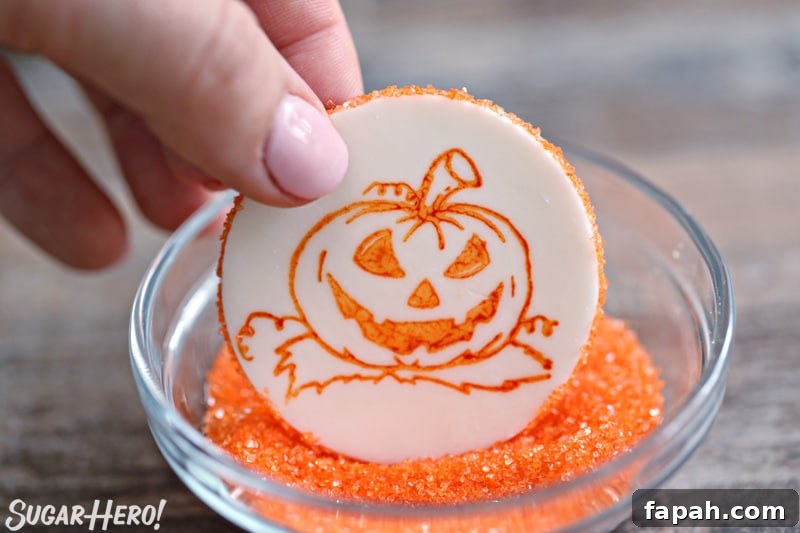 Stamped Halloween Cupcakes - putting a rim of orange sparkling sugar around a fondant circle stamped with an orange pumpkin | From SugarHero.com