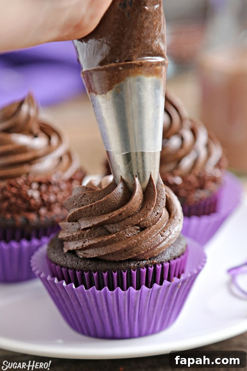 Stamped Halloween Cupcakes - piping chocolate frosting on a chocolate cupcake | From SugarHero.com