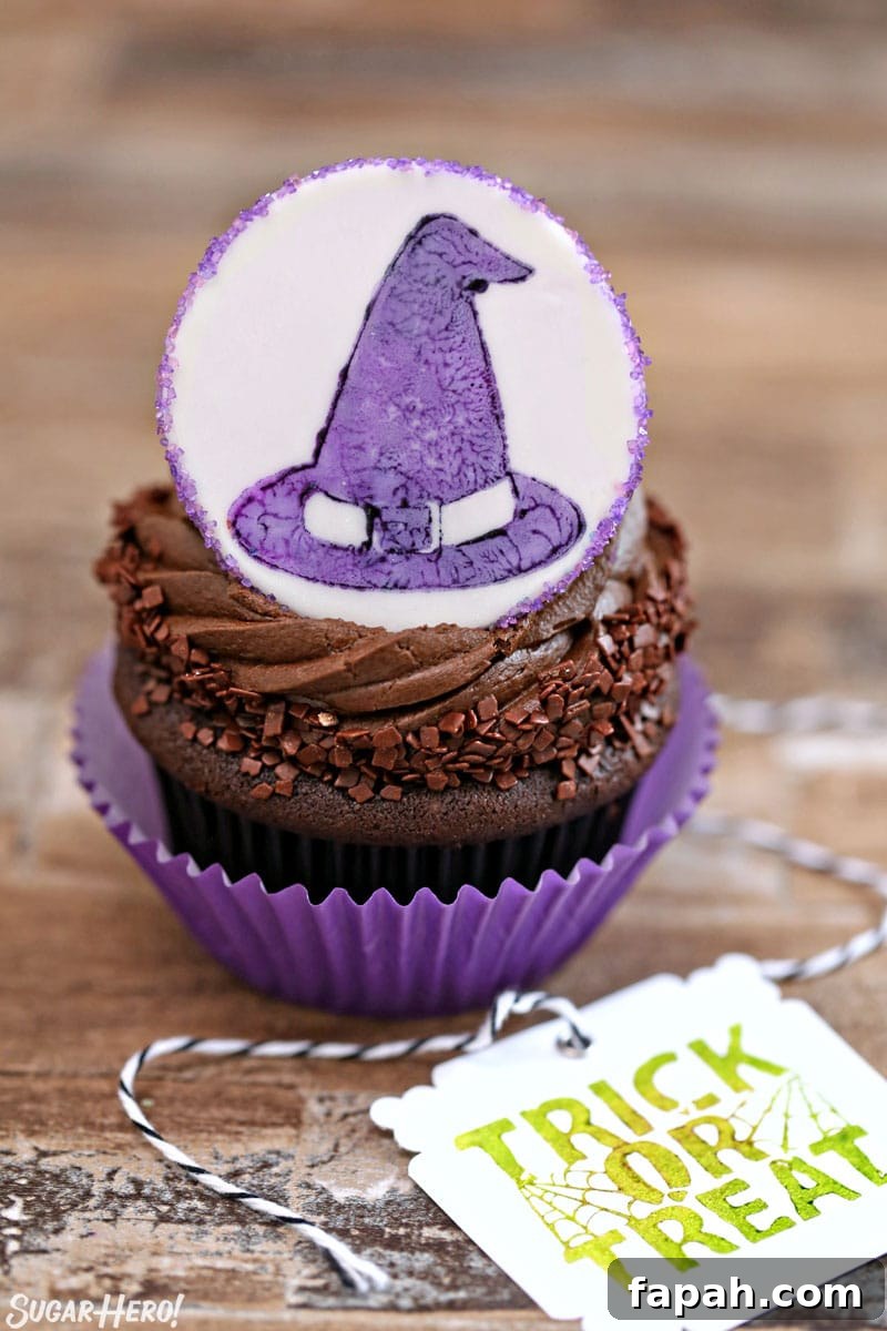 Stamped Halloween Cupcakes - close-up of chocolate cupcake with fondant circle on top with witch hat design | From SugarHero.com