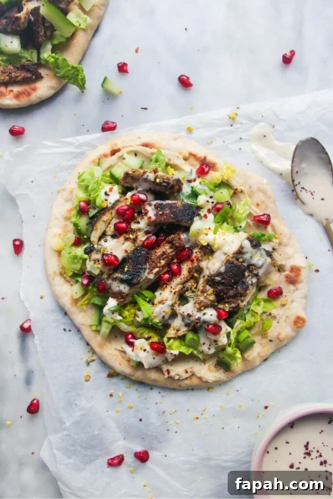 Chicken shawarma wrap on a grey marble background with a small bowl of tahini sauce on the side.