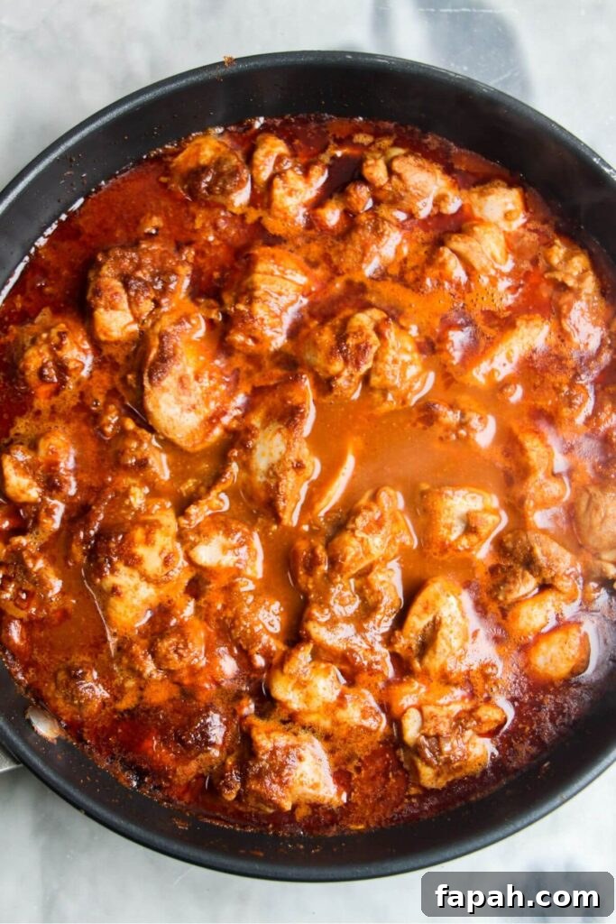 Stock and passata added to diced chicken and spices in a small frying pan.