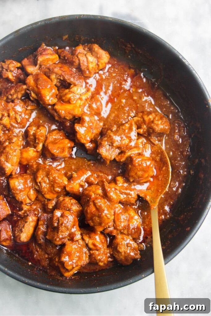 Thickened chicken rogan josh in a small frying pan with a gold spoon inside.