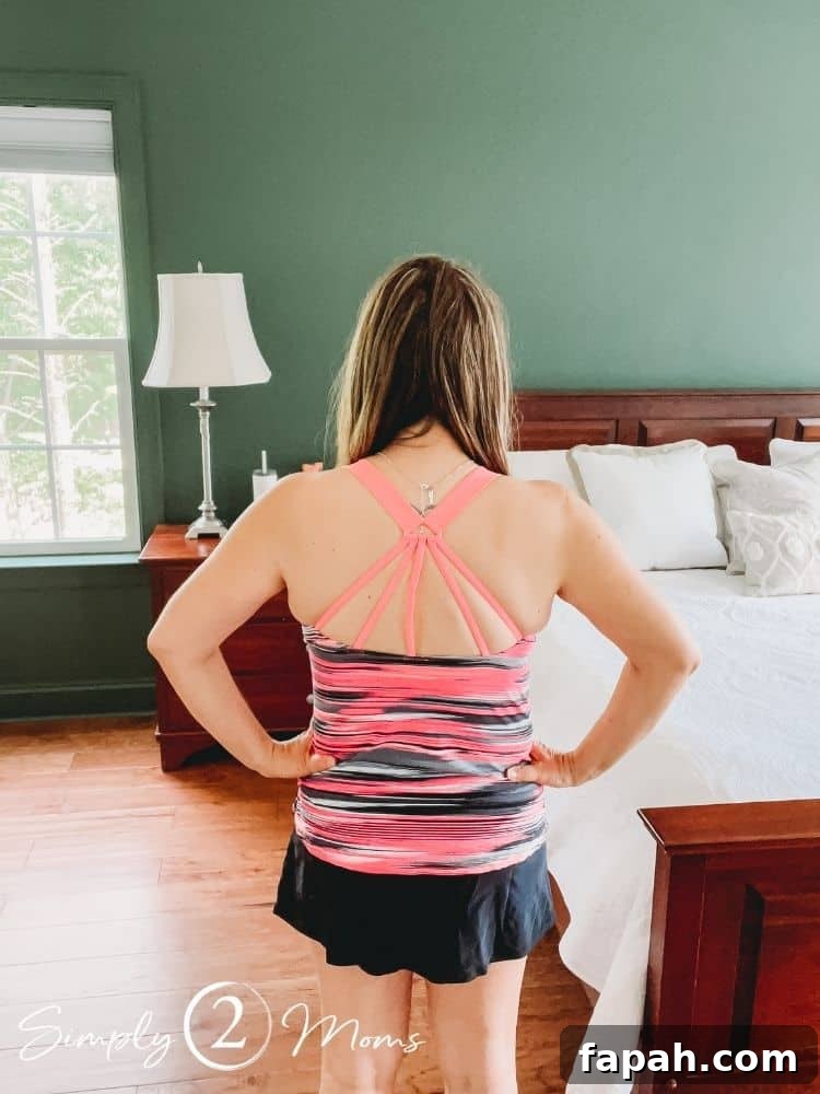 Woman wearing a striped tankini top with strap detailing in the back and swim skirt.