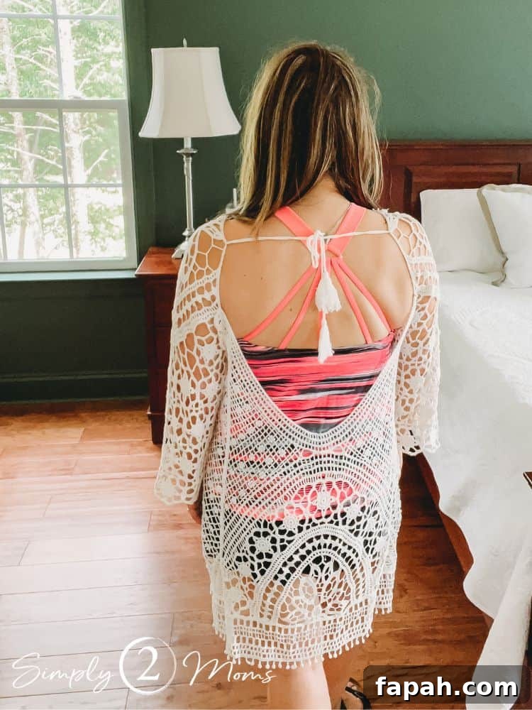 Woman wearing a white lace crochet swim coverup dress with a deep V back and tassels on the tie back closure
