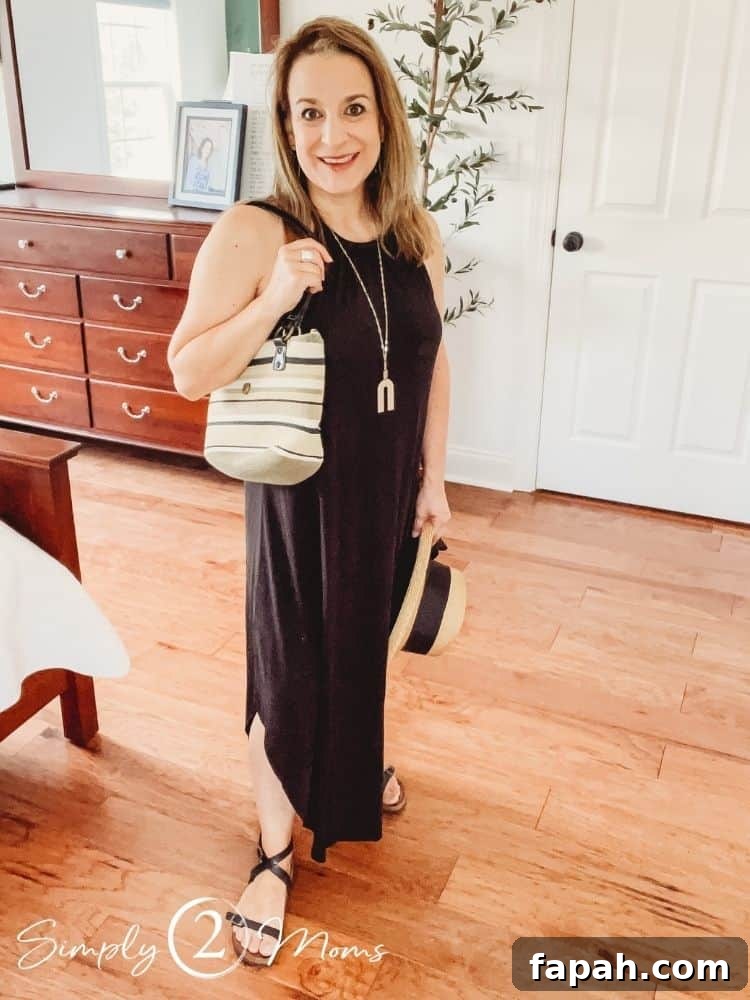 Woman wearing a high neck sleeveless maxi sundress with a striped straw shoulder bag.