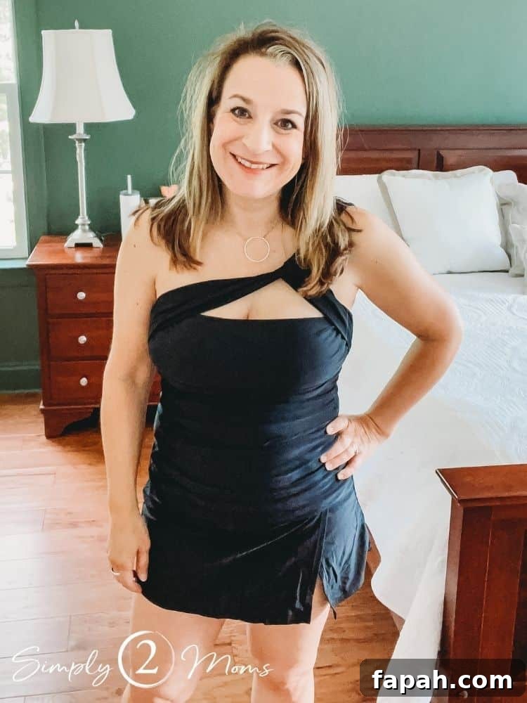 Woman wearing a black bandeau tankini top with one shoulder strap and swim skirt bottom