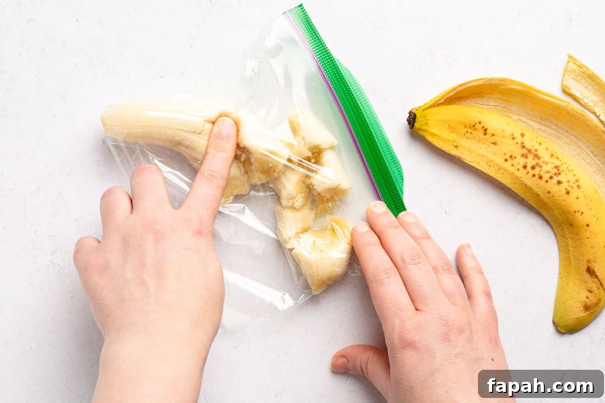 banana inside zip top bag with finger pressing on banana through the bag
