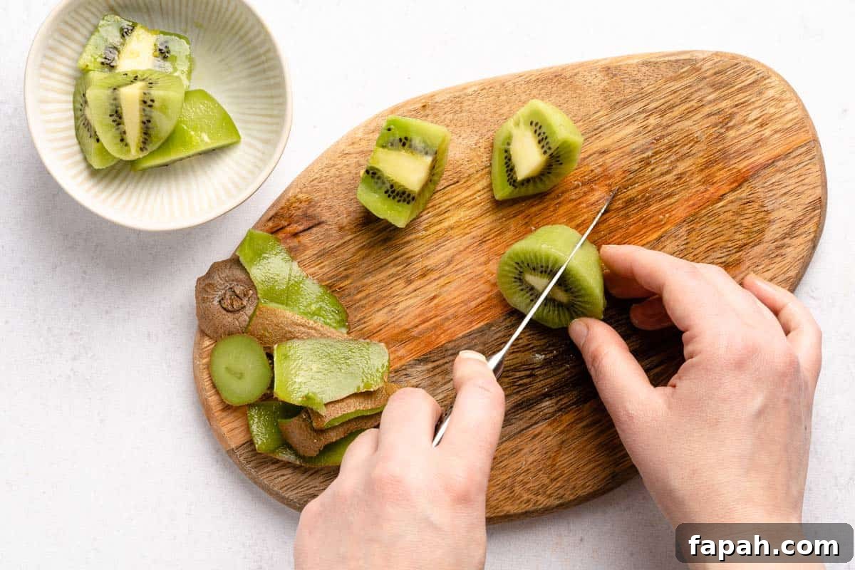 cutting peeled kiwi into quarters with bowl of kiwi on side