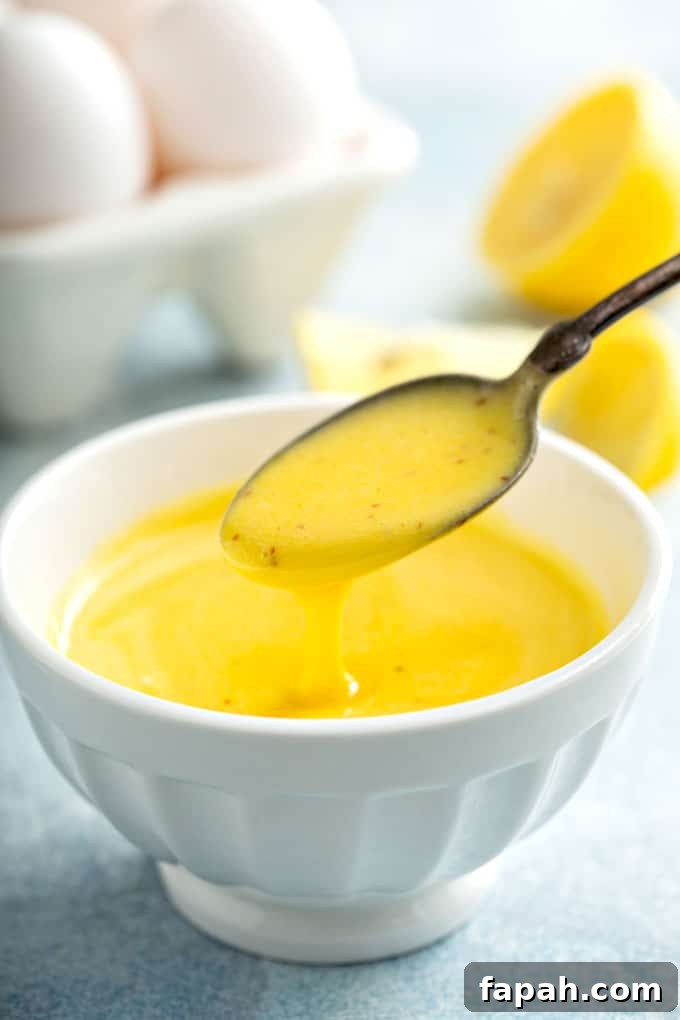 Spoon pouring Hollandaise sauce into a white bowl.