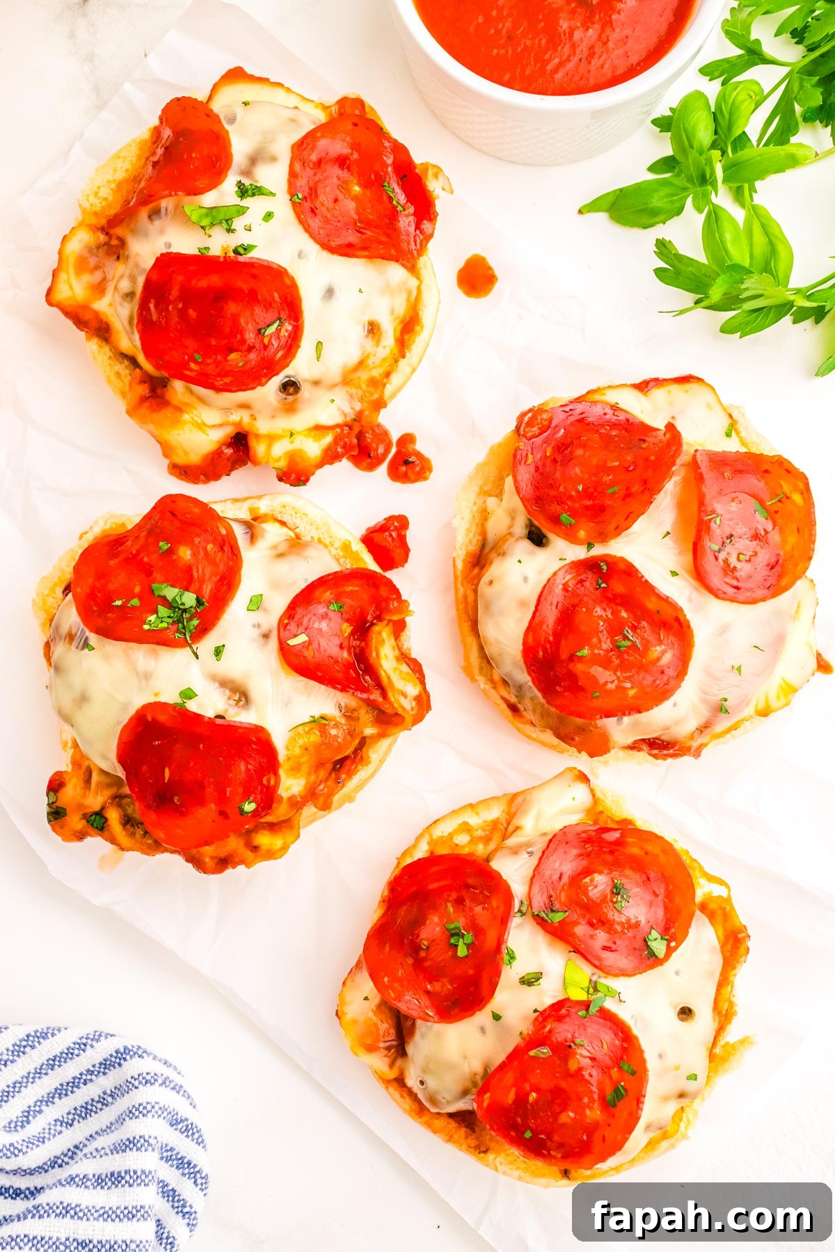 Pizza Burger Recipe: How to Make Savory Pizza-Style Burgers 9 Four pizza burgers without the top bun on them so you can see the beef patty, sauce, melted mozzarella cheese, and pepperoni.