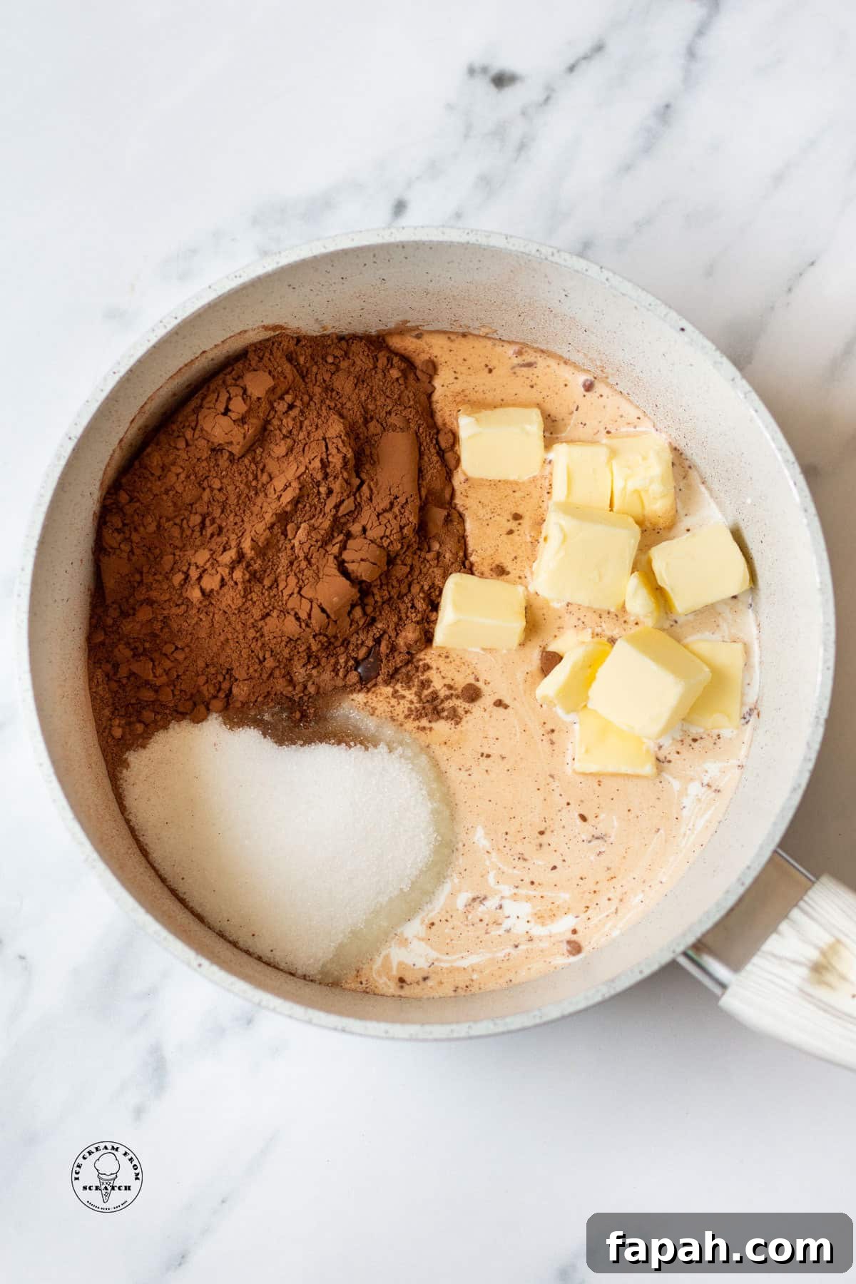 the ingredients for hot fudge sauce, in a saucepan, including sugar, cocoa powder, and cubed butter.