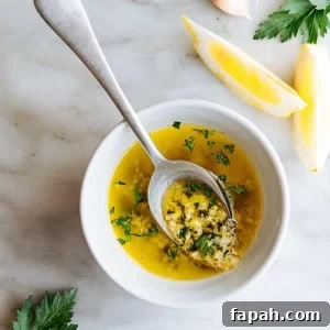 Lemon Garlic Butter Sauce served in a white bowl with a serving spoon on a white marble board